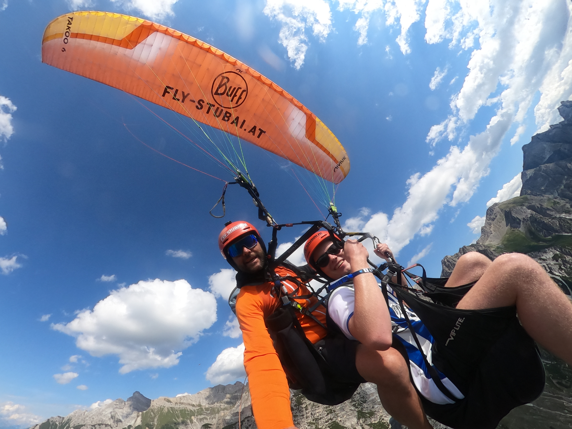 Tandem-Paragliding über den Stubaier Alpen – lachender Gast und Pilot in der Luft