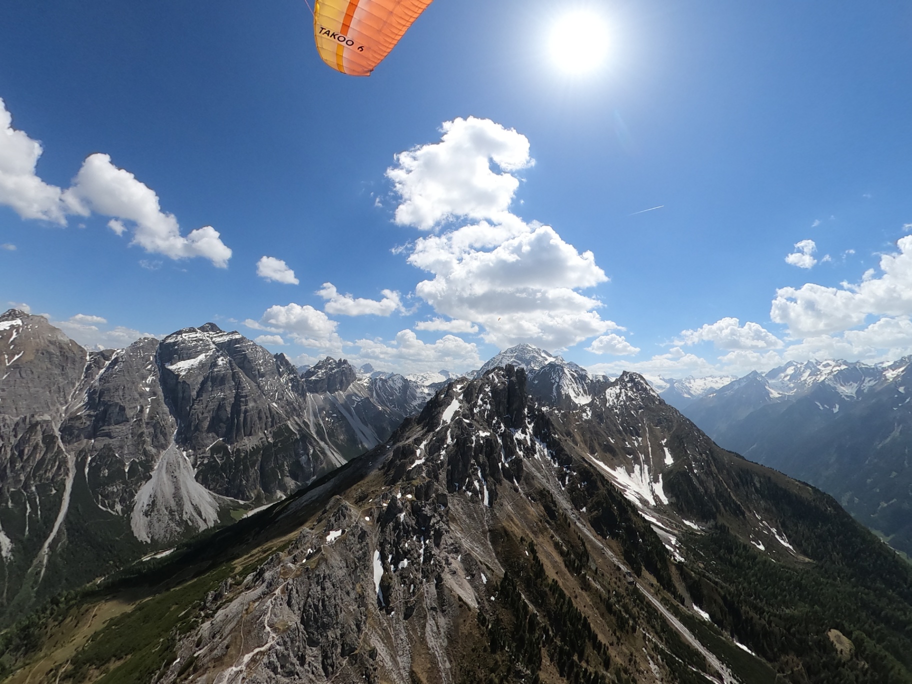 Panoramablick aus dem Tandemflug auf die Stubaier Alpen mit Wolken und Sonnenlicht