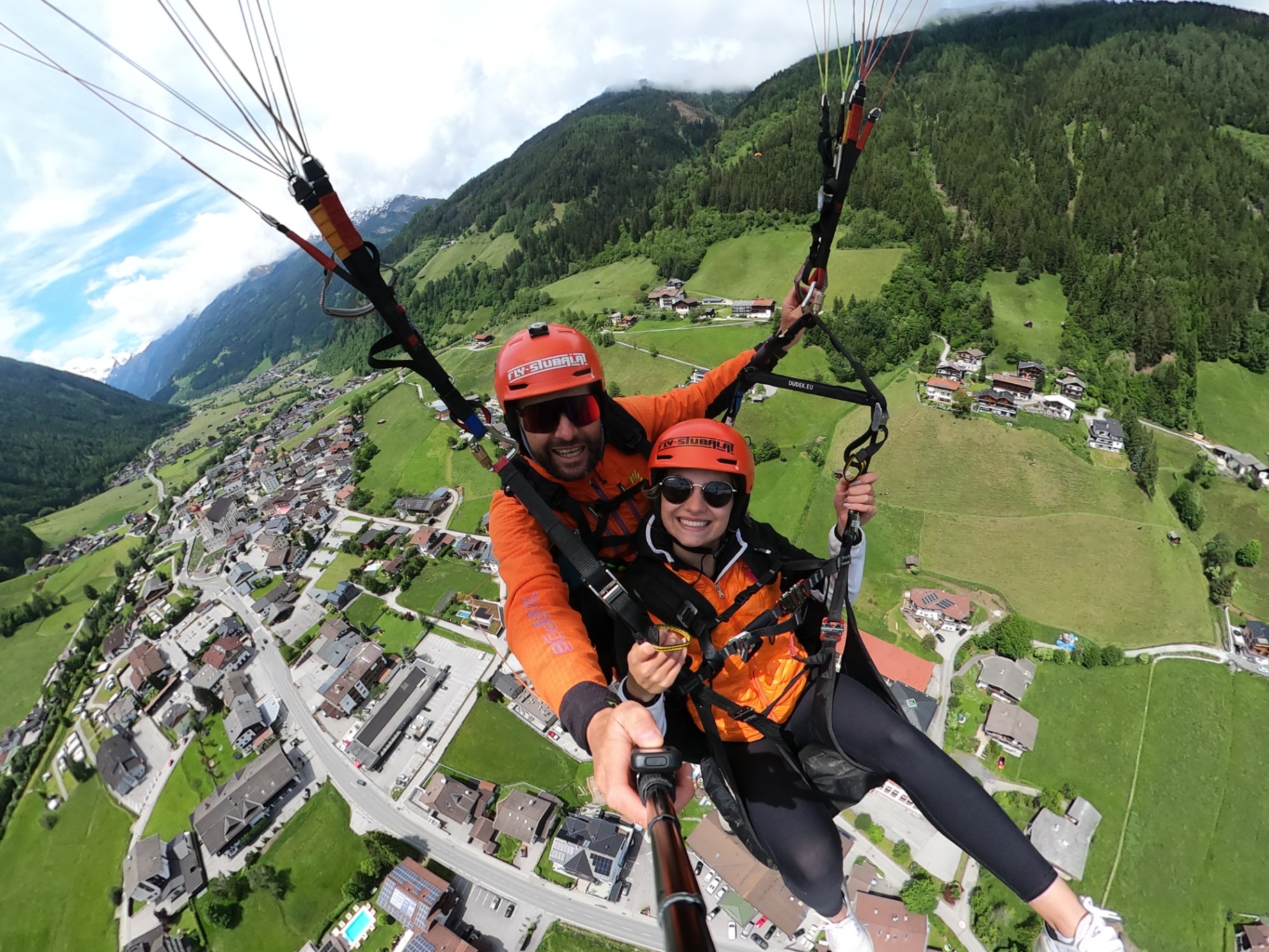 Tandemflug über Neustift mit Blick auf Ort, Wiesen und Berge im Stubaital
